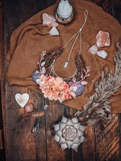 an arrangement of flowers, feathers and candles on a brown blanket next to a candle