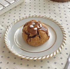 a chocolate chip cookie on a white plate with silverware next to the tablecloth