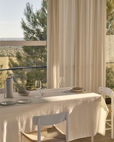 the table is set for two in front of an open window with white drapes