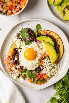 an egg is sitting on top of a plate with rice, avocado and salsa