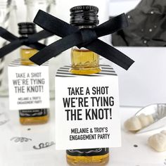 there are two small bottles with black ribbon on them that say take a shot, we're tying the knot