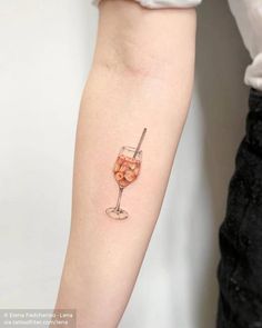 a woman's arm with a wine glass tattoo on the left side of her arm