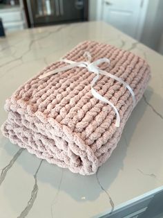 a stack of pink knitted towels tied up on top of a counter