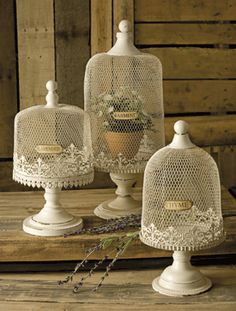 three white birdcages sitting on top of a wooden table next to each other