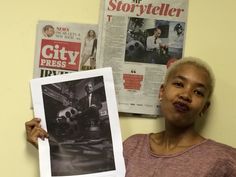 a woman is holding up a newspaper and posing for the camera