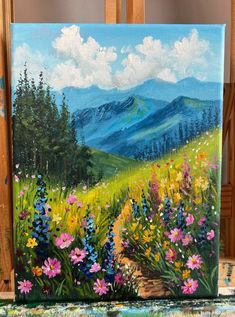 a painting of mountains and flowers on a easel