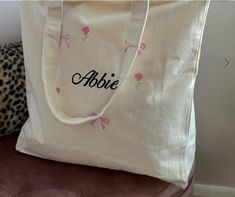 a white tote bag sitting on top of a chair next to a leopard print pillow