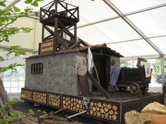 there is a small structure made out of logs in the middle of a tented area