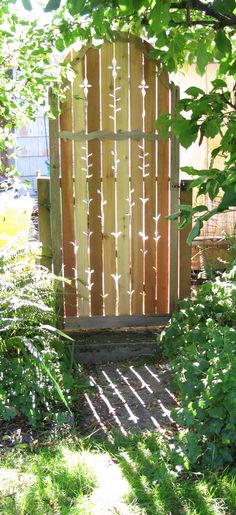 a wooden gate surrounded by green plants and trees