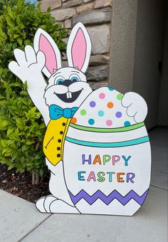 a cardboard easter bunny with an egg in it's lap sitting on the sidewalk