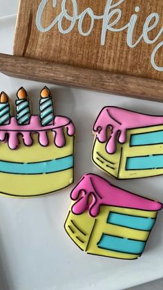 two decorated cookies sitting on top of a white plate next to a wooden sign that says cookies