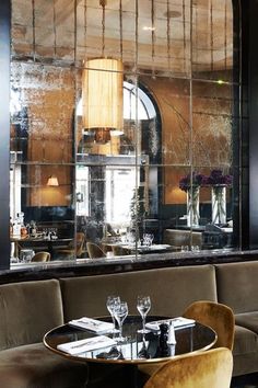 a restaurant with tables, chairs and large mirrors