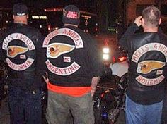 three men in black leather jackets standing next to each other on the street at night