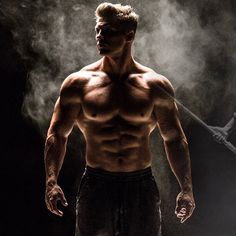 a shirtless man standing in the dark with steam coming out of his chest and arms