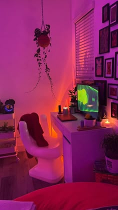 a room with a desk, chair and television in the corner is lit up by purple light