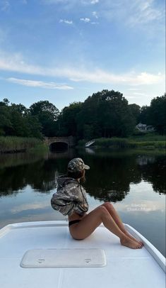 a woman is sitting on the back of a boat in front of trees and water