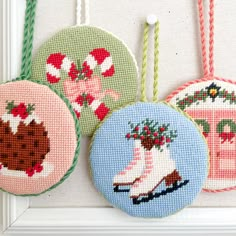 three cross stitch ornaments hanging on a wall