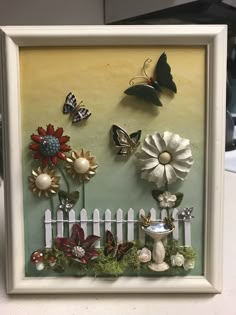 a white frame with flowers and butterflies on the wall next to a picketed fence