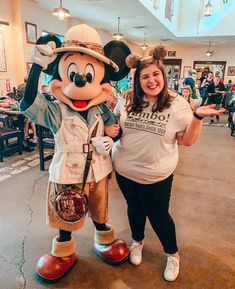 a woman standing next to a mickey mouse