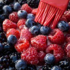 blueberries, raspberries and strawberries are being brushed with a red brush