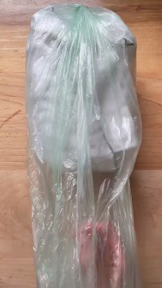 a plastic bag filled with pink shoes on top of a wooden floor