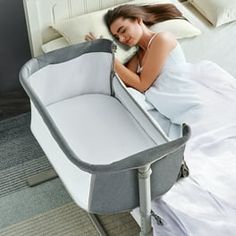 a woman laying on top of a bed next to a baby crib