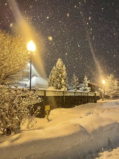 a snow covered street light in the middle of a night time scene with lots of snow