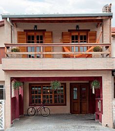 a bicycle parked in front of a house with two balconies on the second floor