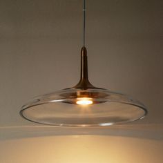 a clear glass light fixture hanging from a ceiling in a room with white walls and flooring