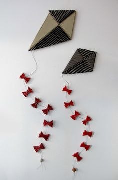 two kites are hanging on the wall with strings attached to them, one is red and the other is black