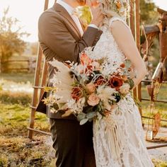 a bride and groom kissing in front of an old fashioned wooden swing with flowers on it