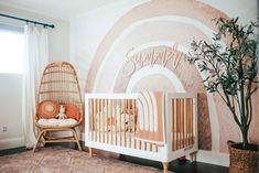 a baby's room with a crib, chair and potted plant