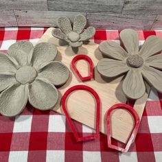 some clay flowers are sitting on a table with red and white checkered cloth next to them