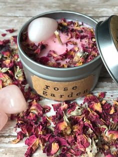 a tin filled with pink flowers sitting on top of a wooden table next to two soap balls