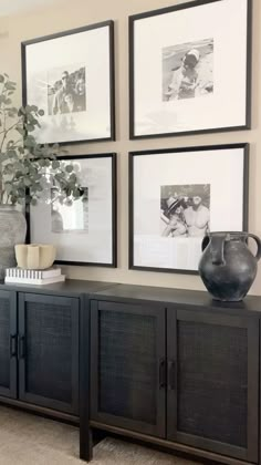 a living room with pictures on the wall and a vase sitting on top of it