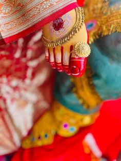 the feet of a woman in red and gold dress with jewelry on her feet, close up