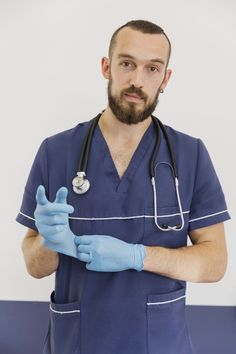 a man in scrubs and blue gloves is holding his hand up to the camera