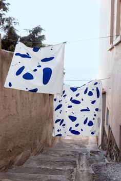 an alley way with blue and white cloths hanging from the clothes line above it