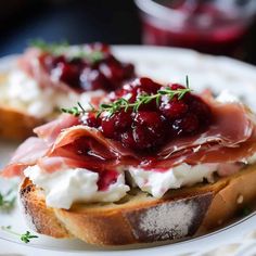 two pieces of bread with cream cheese and cranberry sauce on them, sitting on a plate