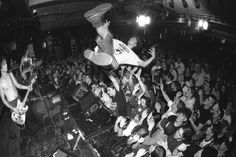 black and white photograph of a man on stage with guitar in front of an audience