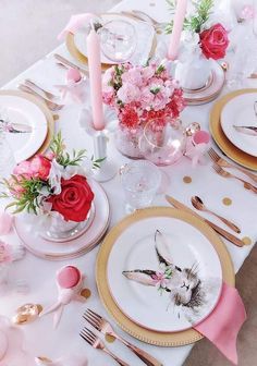 the table is set with pink and gold plates, silverware, and flowers in vases