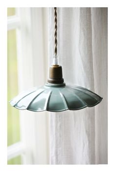 a light that is hanging from the ceiling in front of a window with white curtains