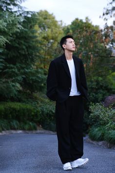 a man standing in the middle of a road wearing a black suit and white t - shirt