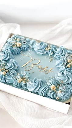 there is a blue cake in the box on the white tablecloth with it's name