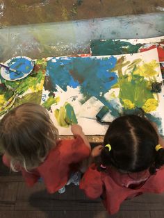 two young children painting on canvases in an art class