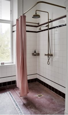 a bathroom with a pink shower curtain next to a window