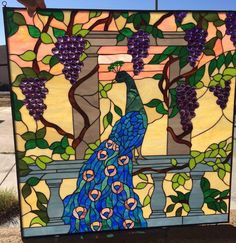 a stained glass window with a peacock on it's side and grapes in the background