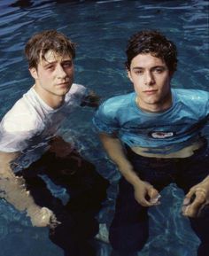 two young men standing in the water next to each other