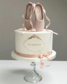 a white cake with pink ballet shoes on top