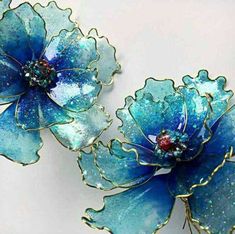 two blue flower brooches sitting on top of each other